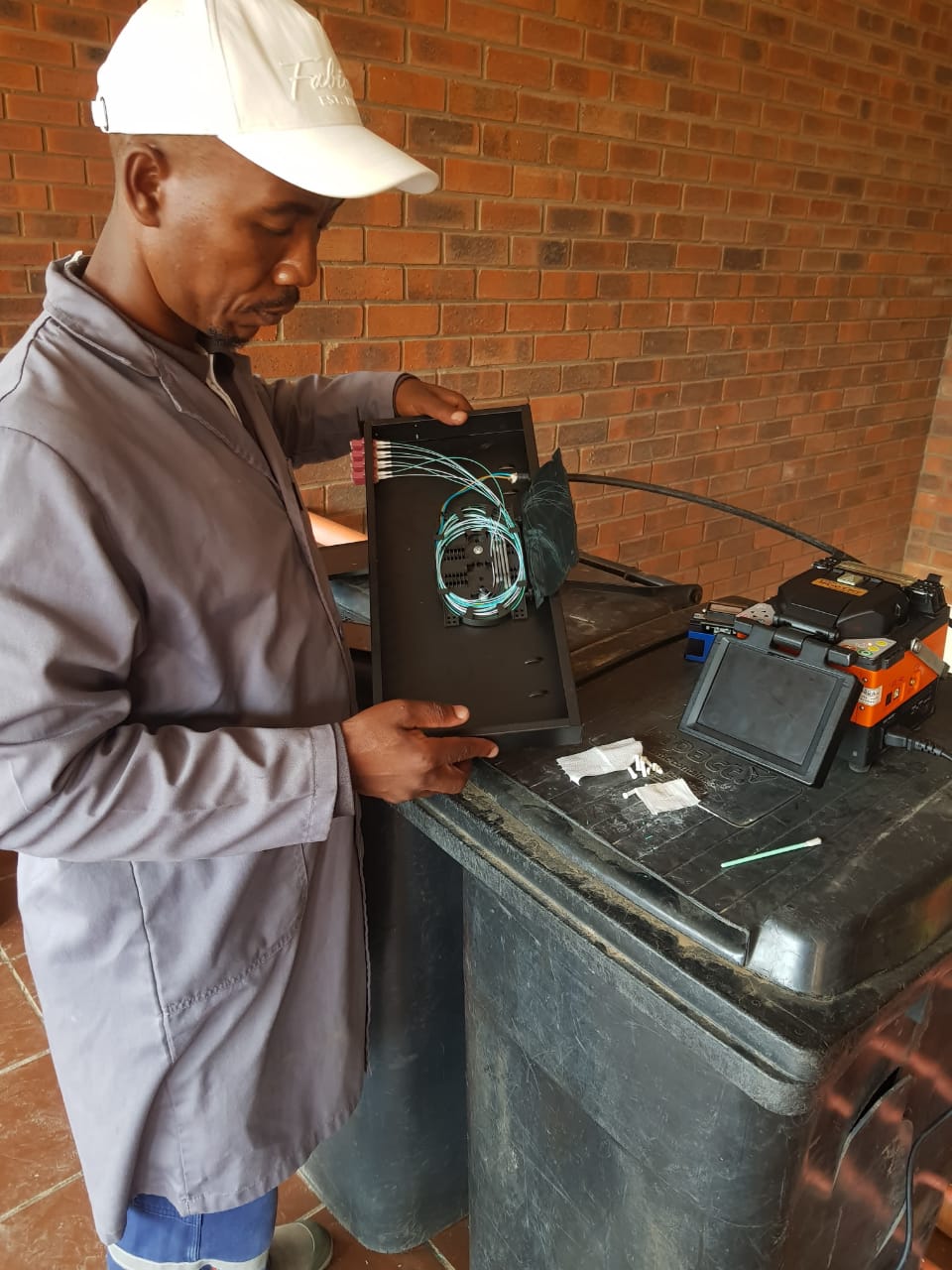 Global IT Systems technician splicing fiber optic cable with a fusion splicer